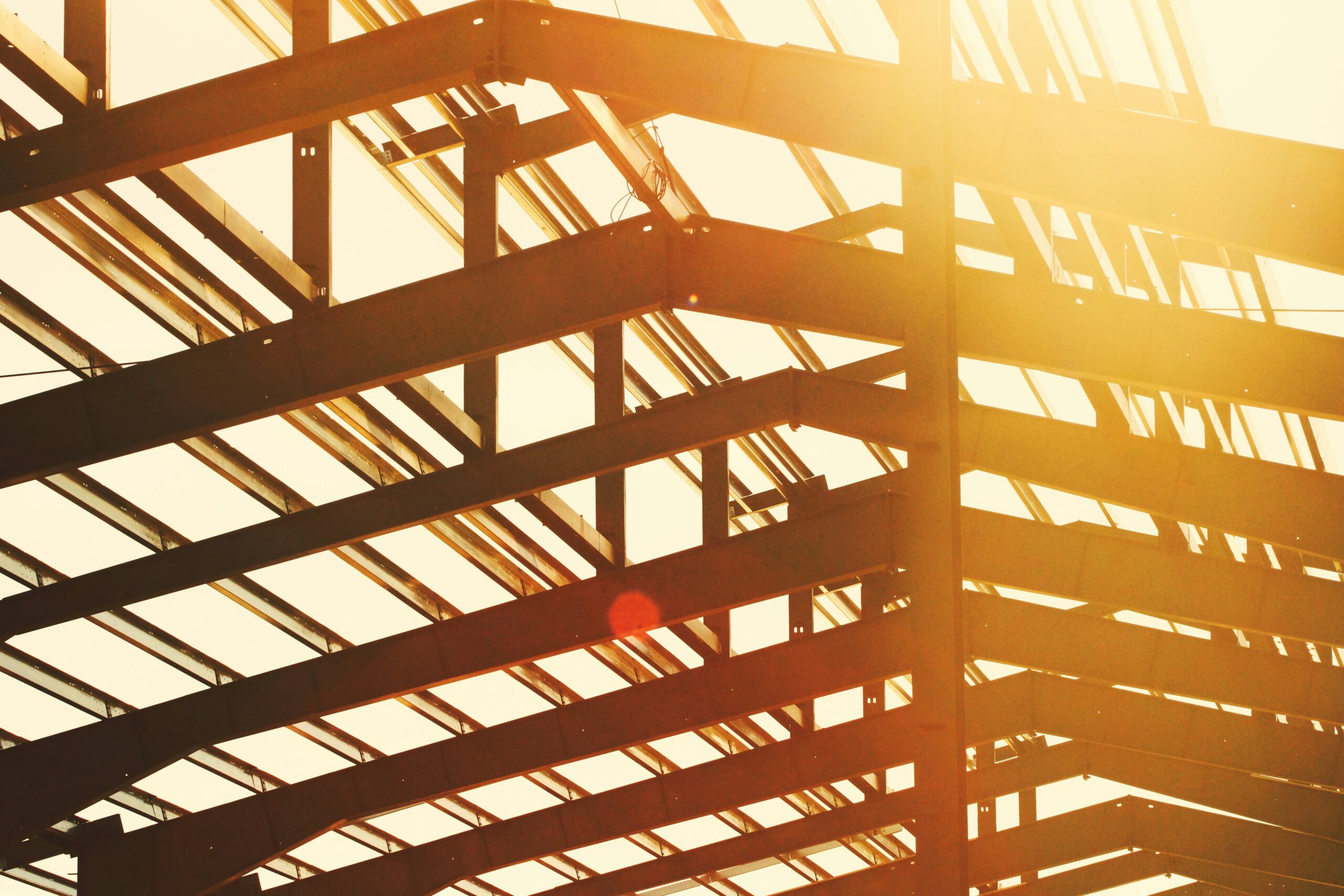 A steel framework is being constructed. There is a warm light and a lens flare.