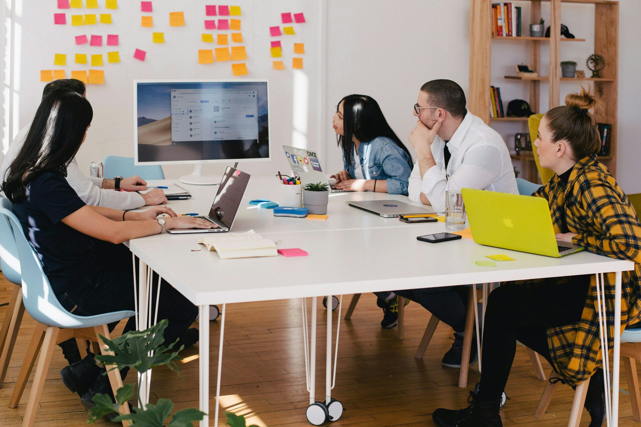 A group of people sitting at a table around a monitor displaying a mockup.